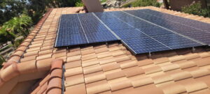 1000292322 - Desert Sands Contracting Solar panels installed on a terracotta-tile roof in a sunny yard with palm trees nearby (informative)