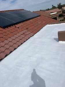 IMG_2320 - Desert Sands Contracting Rooftop with red clay tiles and solar panels on the left, white flat roof in the foreground, blue sky above.