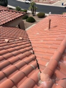 IMG_2331 - Desert Sands Contracting View from a terracotta tiled roof showing a split seam between sections and a vent pipe nearby, with a street in the distance.