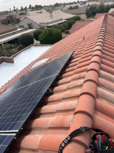 IMG_2333 - Desert Sands Contracting Solar panel installed on a clay tile roof, with a suburban neighborhood in the background.