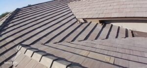 PHOTO-2025-02-01-15-52-42_1 - Desert Sands Contracting Sloped brown tiled roof with overlapping panels under a clear blue sky.