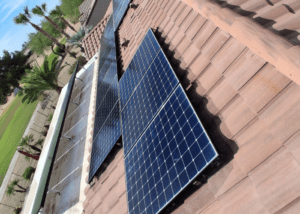 dsr_solar services - Desert Sands Contracting Solar panels installed on a brown tiled roof, angled to capture sunlight in a residential yard setting.